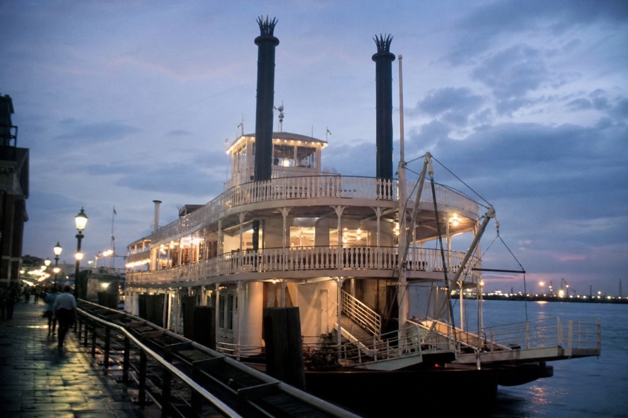 Steamboat NATCHEZ tied up at the Toulouse Street Wharf at dusk with her decks lit and the gangway down