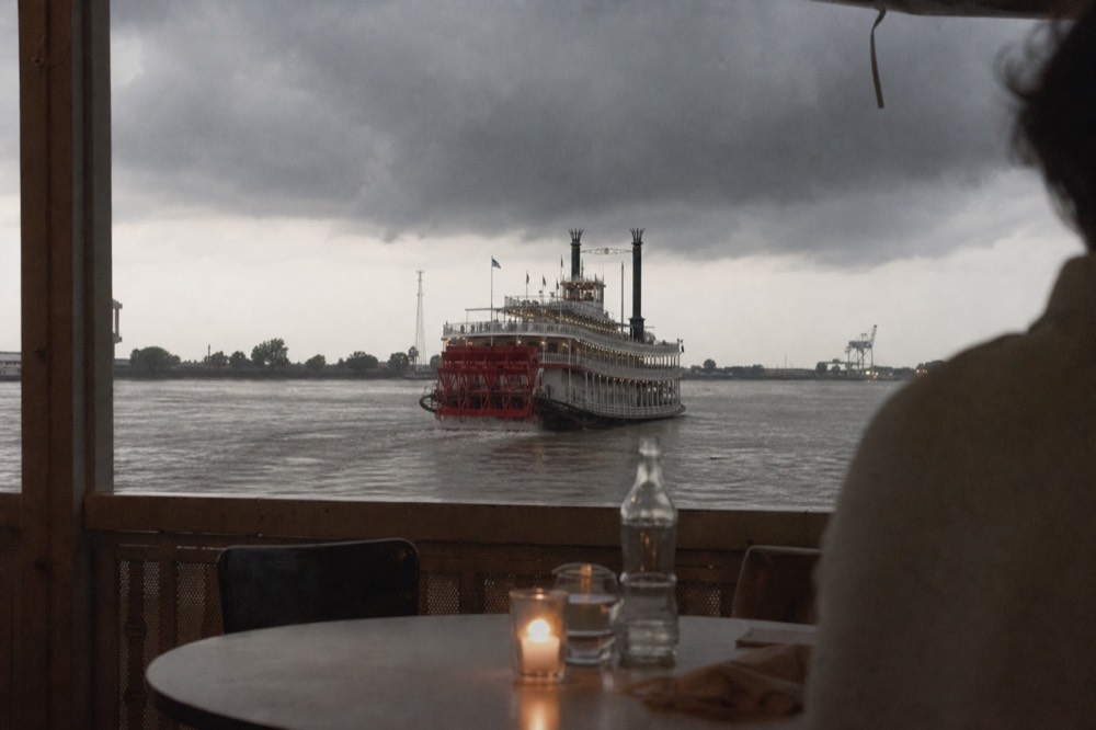 Dark summer storm clouds gathering over the Mississippi with a paddlewheeler heading back toward the city wharves