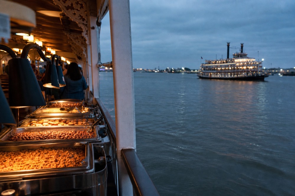 Creole buffet line on a riverboat with trays of jambalaya, red beans and bread pudding under warming lamps